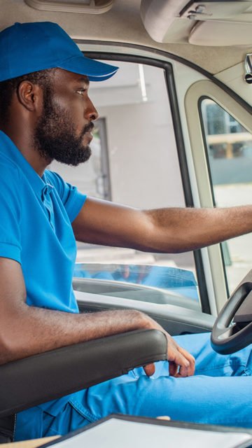Black male in blue uniform driving truck